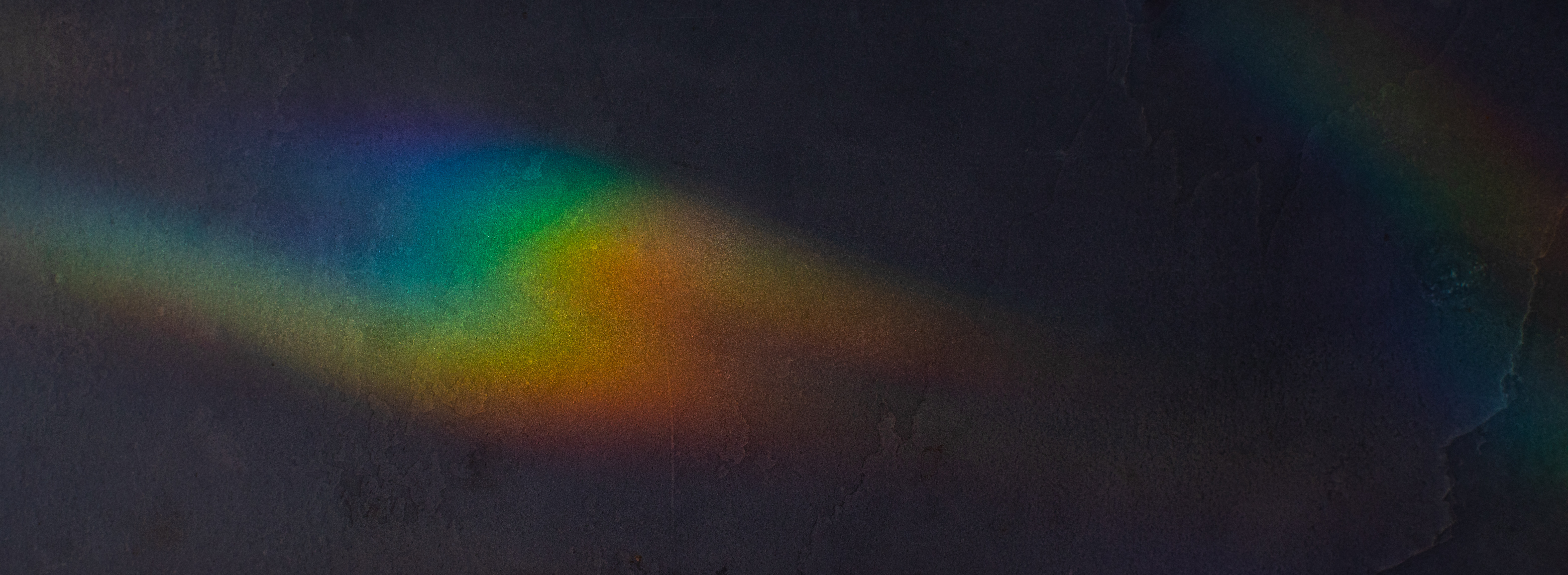 A rainbow falls across a dark wooden surface.